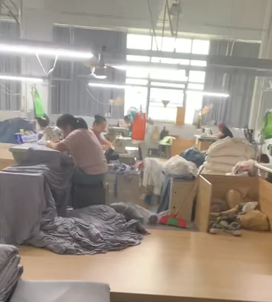 The sewing and finishing floor, with cut goods staged at the tables